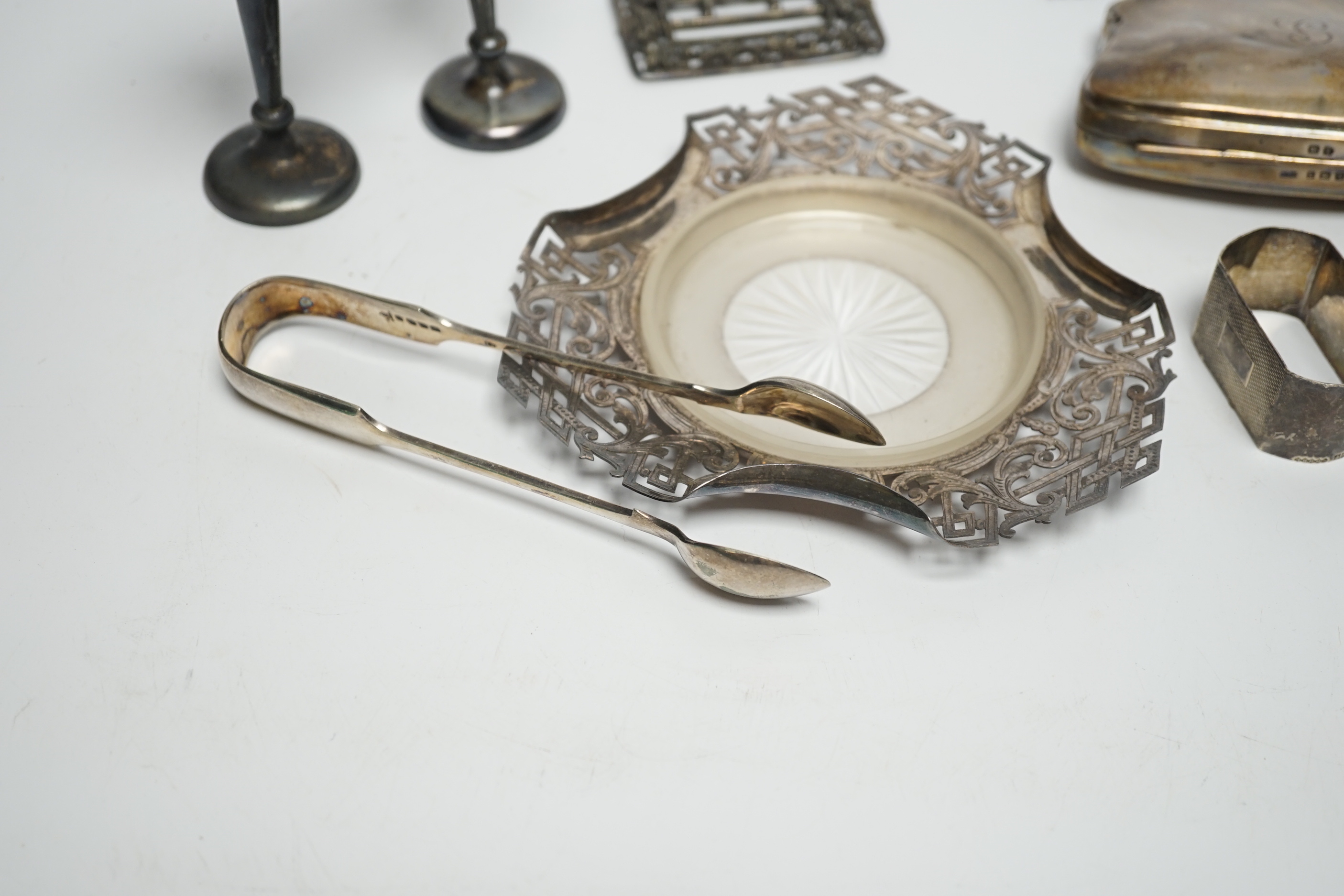 A pair of Edwardian silver mounted posy vases, Birmingham, 1902, weighted, 11.1cm, a silver purse, two silver napkin rings, silver butter dish stand, a silver belt buckle and a pair of plated sugar tongs.